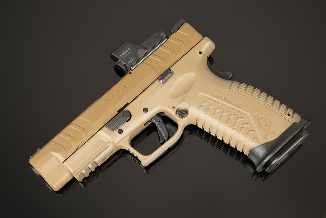 A Springfield Armory XD-M Elite OSP 10mm pistol is displayed in the Desert FDE finish. Both the polymer frame and the forged steel slide feature matching Cerakote coating for durability and a uniform appearance. The pistol includes a 4.5-inch match-grade barrel, striker-fired system, and ambidextrous controls. Its optic-ready slide cut allows for mounting red dot optics, while the factory fiber optic front sight and U-notch rear sight are also visible. The Desert FDE finish resists wear from holsters and field use while giving the handgun a distinctive appearance. Like other XD-M Elite variants, it carries 16+1 rounds of 10mm Auto. This image highlights the cosmetic difference of the FDE model while reinforcing that performance remains identical.