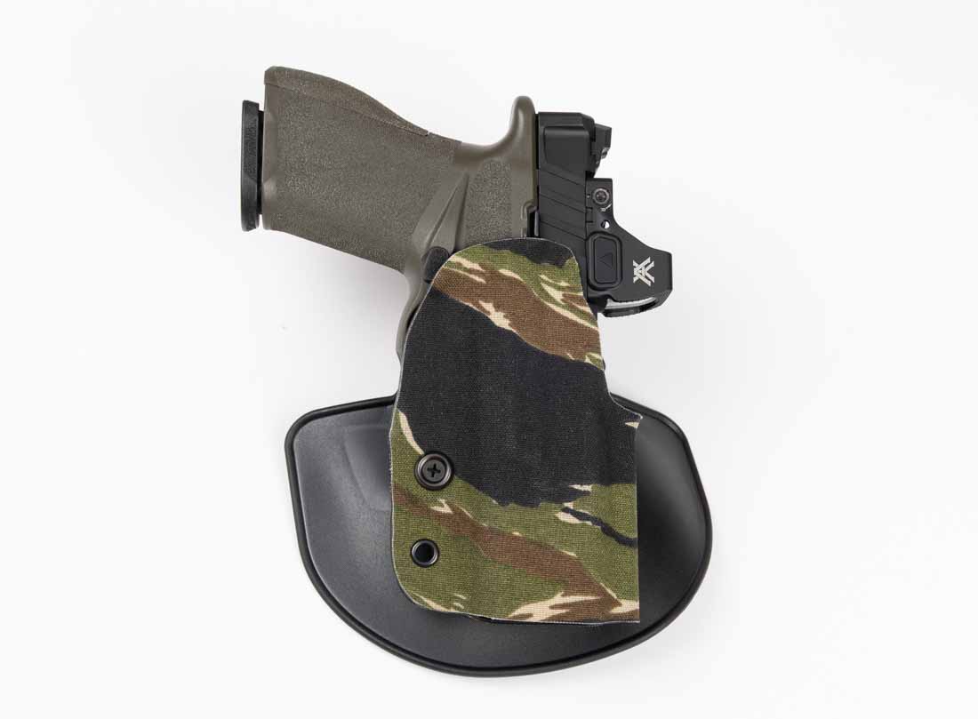 The image shows a Springfield Armory Echelon 4.0C pistol holstered in a Safariland Gravity outside-the-waistband paddle holster. The holster’s molded SafariLaminate shell is shaped specifically to fit the Echelon’s frame and trigger guard, providing passive retention with an audible click. The pistol is optic-equipped, and the holster’s low-cut front clears the sight without contact. The Cordura wrap on the exterior adds texture and durability to the holster body. The paddle attachment secures the holster firmly at the wearer’s hip, preventing unwanted movement during draw or reholstering. This setup was tested in both range and daily carry contexts, demonstrating stability, consistent retention, and a smooth draw path. The combination illustrates the Gravity’s suitability for the Echelon platform in both training and concealed carry with a cover garment.