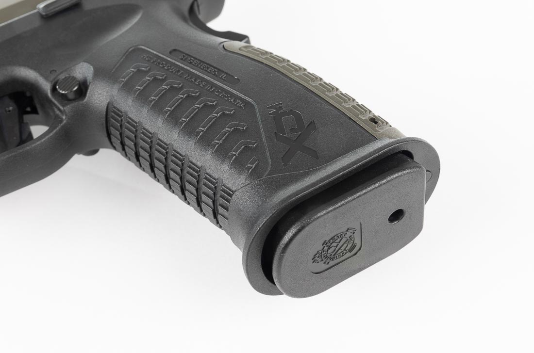A detailed close-up of the Springfield Armory XD-M Elite OSP 10mm pistol shows the magazine well. The frame features a beveled and slightly flared opening, designed to guide magazines quickly into place. This geometry ensures that even under stress or on the timer, reloads are smooth and efficient. The polymer frame is textured for grip, while the magwell design helps ensure reliable seating of the 16-round magazines. Empty magazines drop free cleanly, a point noted in the review during range drills. This detail highlights Springfield’s focus on practical performance rather than purely cosmetic features. The magwell is part of what makes the XD-M Elite series stand out as a serious tool for defensive and range use.