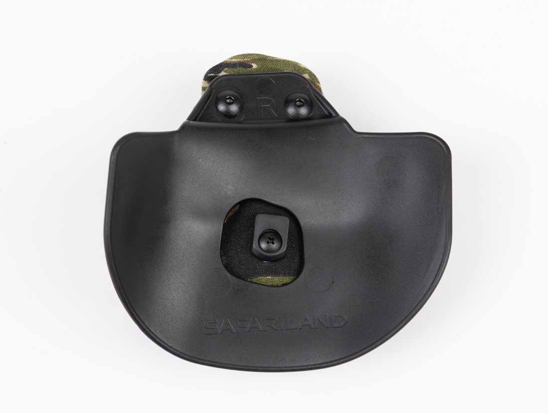 The image shows a close-up view of the paddle attachment used on the Safariland Gravity outside-the-waistband holster. The paddle is wide and slightly curved to match the contour of the body for comfort and stability. Its lower edge features a hooked section designed to catch against the inside of the waistband, preventing the holster from pulling free during a draw. The textured surface helps reduce shifting against clothing. This paddle attaches directly to the holster shell, eliminating extra joints or adapters that could introduce flex. The design allows for quick installation and removal using a pivoting motion while maintaining secure retention when worn. This setup balances accessibility with the stability needed for range use, field carry, or concealed carry with a cover garment.