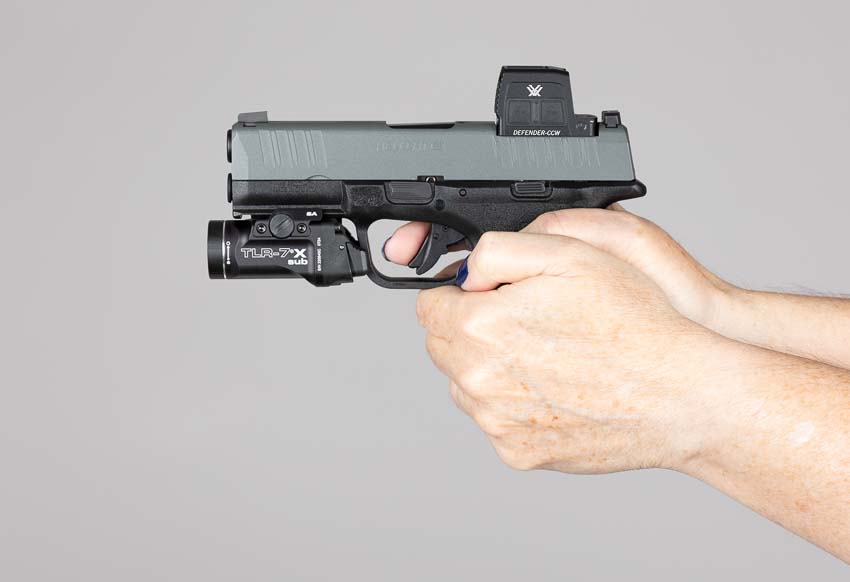 Vortex Defender-CCW Enclosed red dot sight mounted on Springfield Armory Hellcat Pro with Streamlight TLR-7x Sub weapon light during defensive handgun training class. The concealed carry pistol setup combines enclosed optic and compact weapon light for complete low-light defensive capability. Defender-CCW red dot provides fast target acquisition while Streamlight pistol light illuminates threats during realistic shooting scenarios. Training with pistol-mounted optics and weapon lights validates the Hellcat Pro micro-compact configuration for everyday carry applications. The enclosed reflex sight maintains clear dot presentation alongside TLR-7x Sub without interference or co-witnessing issues during live fire. Vortex CCW red dot paired with Streamlight weaponlight creates duty-grade concealed carry setup on subcompact 9mm handgun. Defensive pistol training with enclosed red dot sights demonstrates the Defender-CCW's performance during dynamic shooting drills. Complete EDC handgun configuration featuring micro red dot optic and compact weapon light for real-world self-defense preparedness.