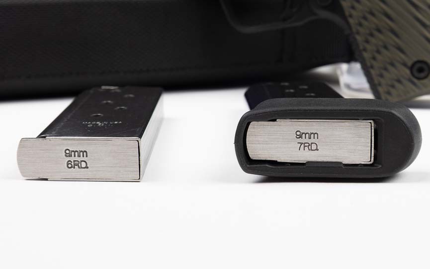 Two stainless steel magazines for the Springfield 911 sit side-by-side, with the flush-fit six-round magazine on the left and the extended seven-round magazine with baseplate on the right. The Springfield 911 9mm review compares magazine options for concealment versus capacity priorities. Extended magazine baseplates improve grip purchase on micro-compact pistols. The Springfield Armory 911 magazines feature witness holes for visual ammunition counts. Flush magazines maximize deep concealment in ankle or pocket holsters. Magazine capacity decisions balance firepower needs against concealability requirements.