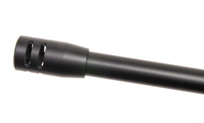 A close-up photograph shows the muzzle brake device attached to the threaded barrel end of the Kalashnikov KR-9 rifle. The Kalashnikov KR-9 features effective muzzle device for recoil management. Pistol caliber carbines benefit from compensator designs. The KUSA 9mm pistol caliber carbine reduces muzzle rise during rapid fire. Blowback-operated firearms utilize threaded barrel accessories. AK-pattern carbines accommodate aftermarket muzzle devices.