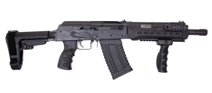 The Kalashnikov Komrad appears in right-side profile, revealing the firearm's distinctive blend of shotgun power and AK-style configuration, including the adjustable gas regulator, Picatinny rails, and magazine well. The Kalashnikov Komrad review details functional features thoroughly. Komrad 12 shotgun evaluation covers operational controls. Russian-inspired shotgun designs incorporate familiar elements. Magazine-fed 12-gauge platforms enable quick ammunition changes. Adjustable gas systems accommodate various shell loads.