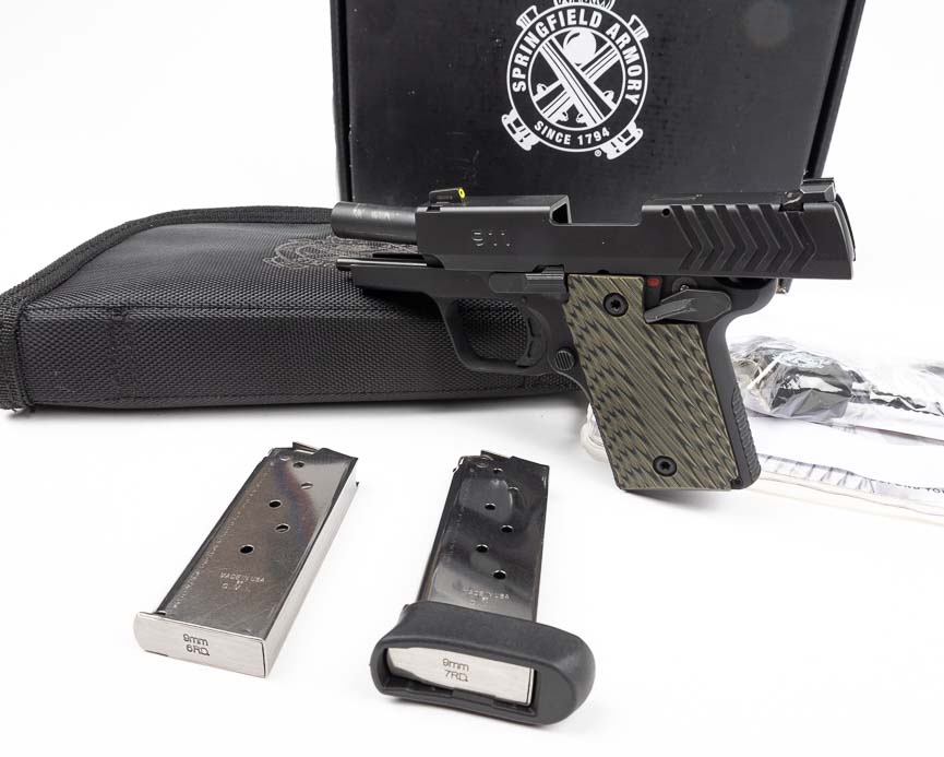 The Springfield 911 9mm pistol rests in its factory carrying case alongside two magazines—one flush-fit six-round and one extended seven-round—plus cleaning supplies and documentation. The Springfield 911 9mm review includes evaluation of both magazine options for carry purposes. Extended magazines improve grip surface area and increase ammunition capacity. The Springfield Armory 911 ships with quality accessories for immediate deployment. Spare magazines ensure adequate ammunition supply for defensive situations. Micro-compact pistols benefit from extended magazine baseplates for enhanced control.