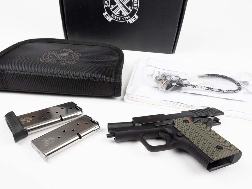The complete Springfield 911 9mm package is laid out showing the pistol, two magazines, factory hard case, cable lock, bore brush, owner's manual, warranty card, and trigger lock arranged neatly on a surface. The Springfield 911 9mm review documents all factory-included accessories and components. Complete firearm packages provide immediate operational capability after purchase. The Springfield Armory 911 includes essential cleaning and safety equipment. Factory documentation covers maintenance schedules and parts diagrams. Trigger locks and cable locks satisfy safe storage legal requirements. Quality manufacturers support products with comprehensive warranty coverage.