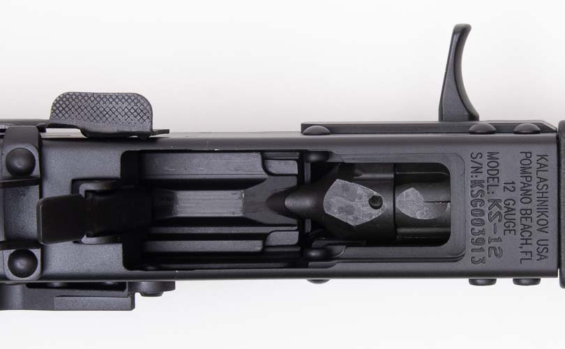 The magazine well of the Kalashnikov Komrad 12 displays the distinctive AK-style magazine insertion point, featuring the rock-and-lock mechanism that securely seats the five-round detachable magazines during loading operations. The Kalashnikov Komrad review examines magazine compatibility thoroughly. Komrad 12 shotgun evaluation tests magazine retention reliability. AK-pattern magazine wells utilize proven designs. Rock-and-lock systems ensure secure magazine seating. Semi-automatic shotguns enable rapid magazine changes.