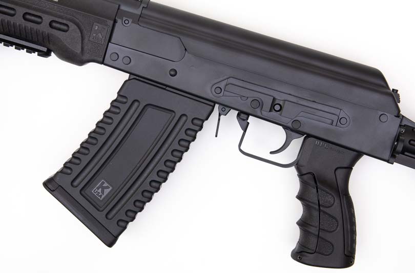 A side-mounted optics rail on the Kalashnikov Komrad KS-12 provides a mounting platform for red dot sights, holographic optics, or magnified scopes, complementing the factory iron sights for enhanced target acquisition. The Kalashnikov Komrad review examines sighting system options thoroughly. Komrad 12 shotgun evaluation tests optic mounting stability. Side-rail optic mounts follow AK-pattern design. Red dot sights improve rapid target engagement. Semi-automatic shotguns benefit from optical enhancement.